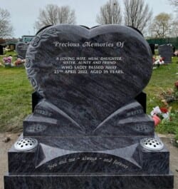 A softly rounded heart memorial, in Bahama Blue granite, adorned with a deeply carved, antique rose edging.